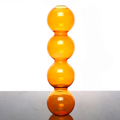 By Levin orange glass flower vase with a modern stacked bubble sphere design on a neutral surface