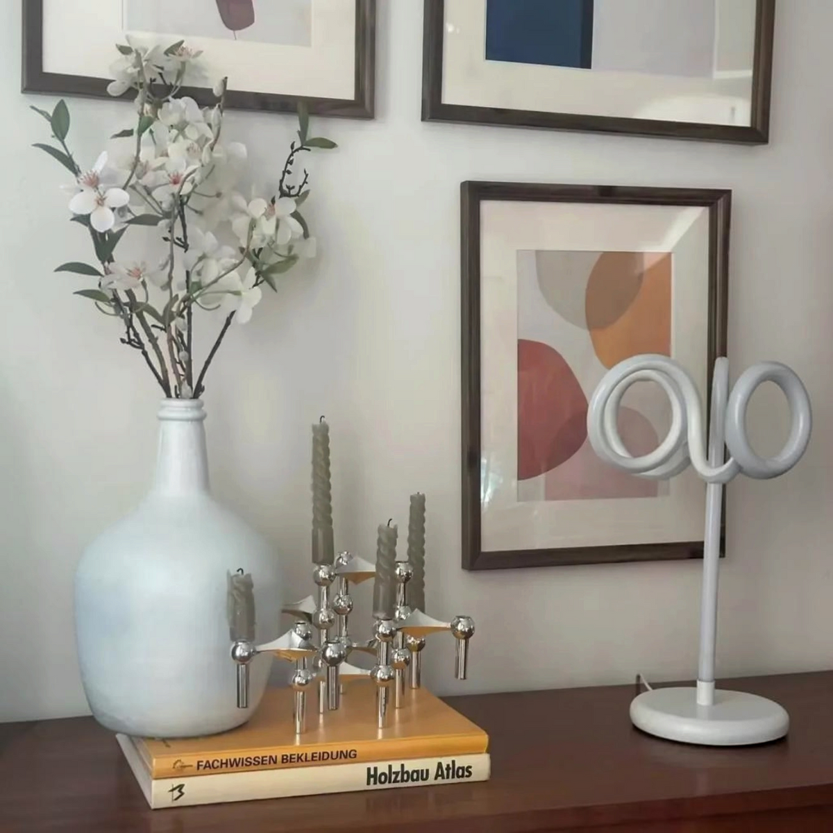 By Levin Scandinavische moleculaire kandelaar van zilverkleurig metaal op een dressoir met boeken en decoratie.