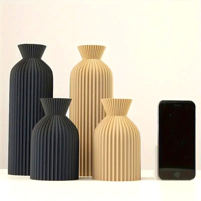 By Levin Nordic pleated plastic vases in black and khaki with a matte finish, shown in various sizes on a table.