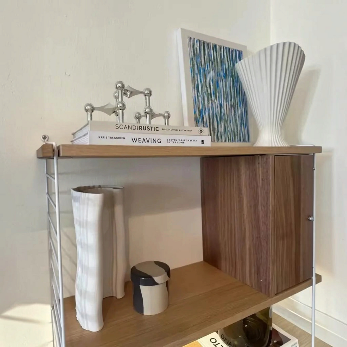 By Levin zilveren moleculaire kandelaar met geometrisch design op een houten wandplank in een modern interieur.