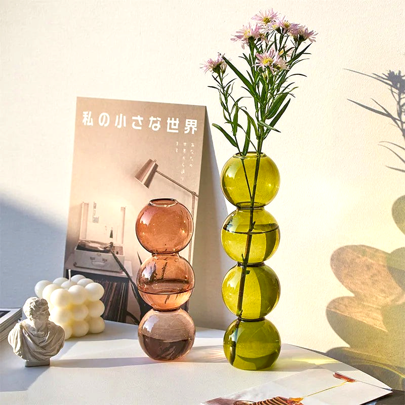 By Levin Nordic bubble glass flower vases in green and brown with stacked sphere design on a minimalist desk