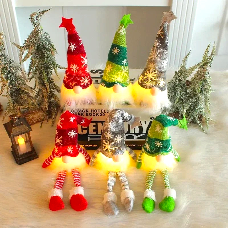By Levin set of six plush Scandinavian Christmas gnomes with LED lights, snowflake hats, and dangling striped legs.